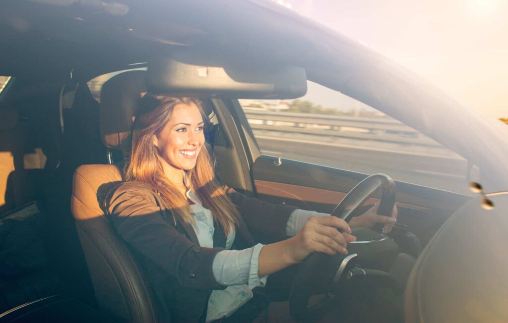 Mulher sorrindo segurando o volante e dirigindo