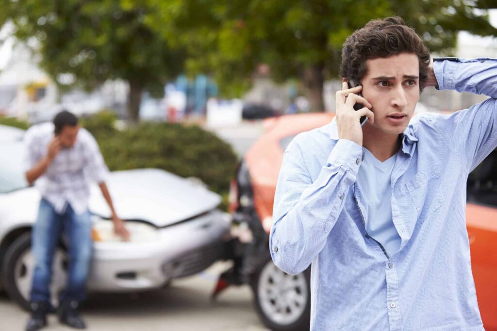 carros batidos e homem no telefone