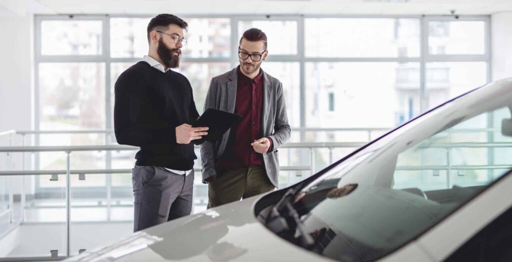Imagem de dois homens negociando a venda de um carro