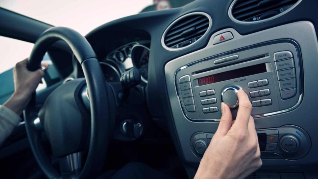 Mão de homem mexendo no volume do carro