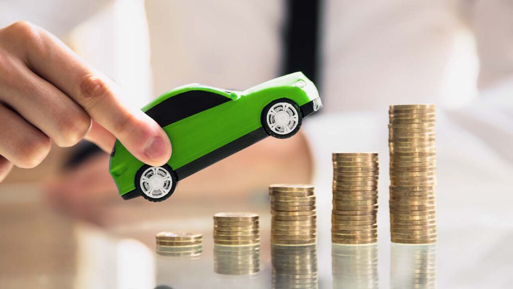 Homem segurando um carrinho de brinquedo na cor verde subindo uma ladeira feita com moedas empilhadas - pagamento na Instacarro