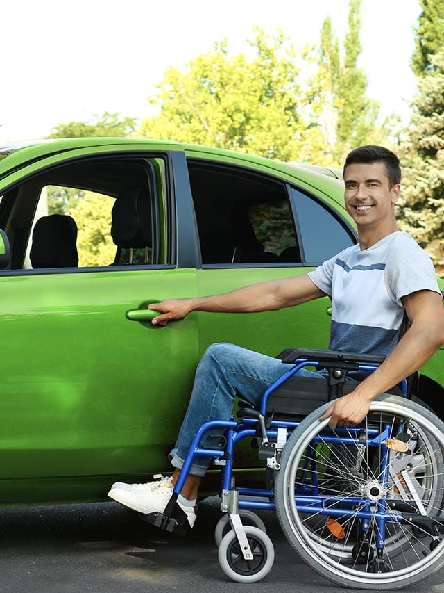Homem cadeirante ao lado de um carro verde abrindo a porta