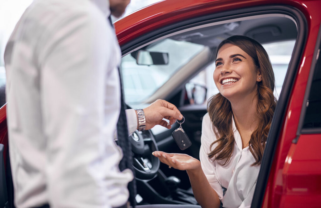 compra carro com nome sujo - mulher sorridente pegando a chave de carro - consórcio