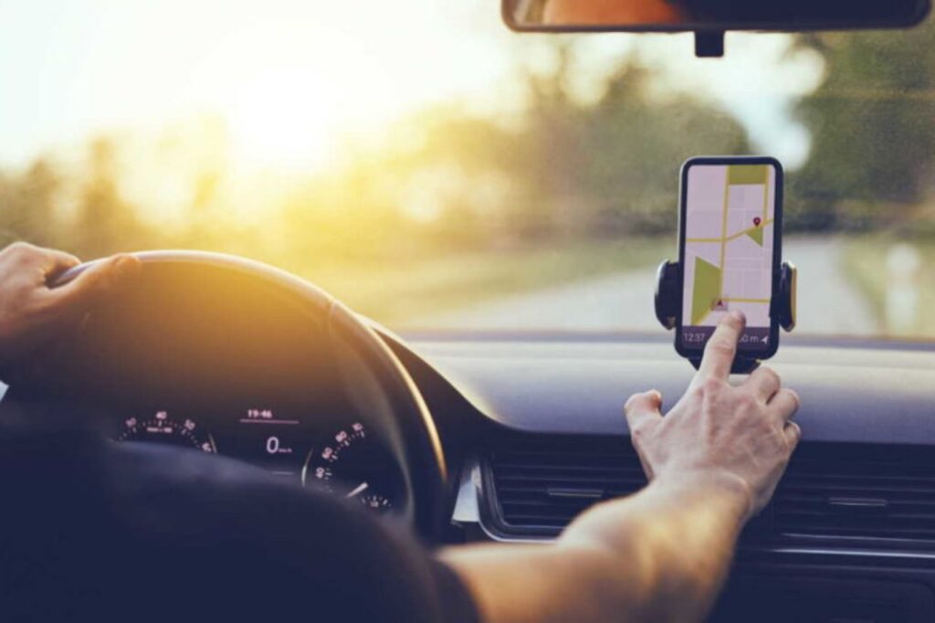 O que está acontecendo com os aplicativos de mobilidade? 5 aplicativos de mobilidade - mão masculina mexendo em celular dentro de carro