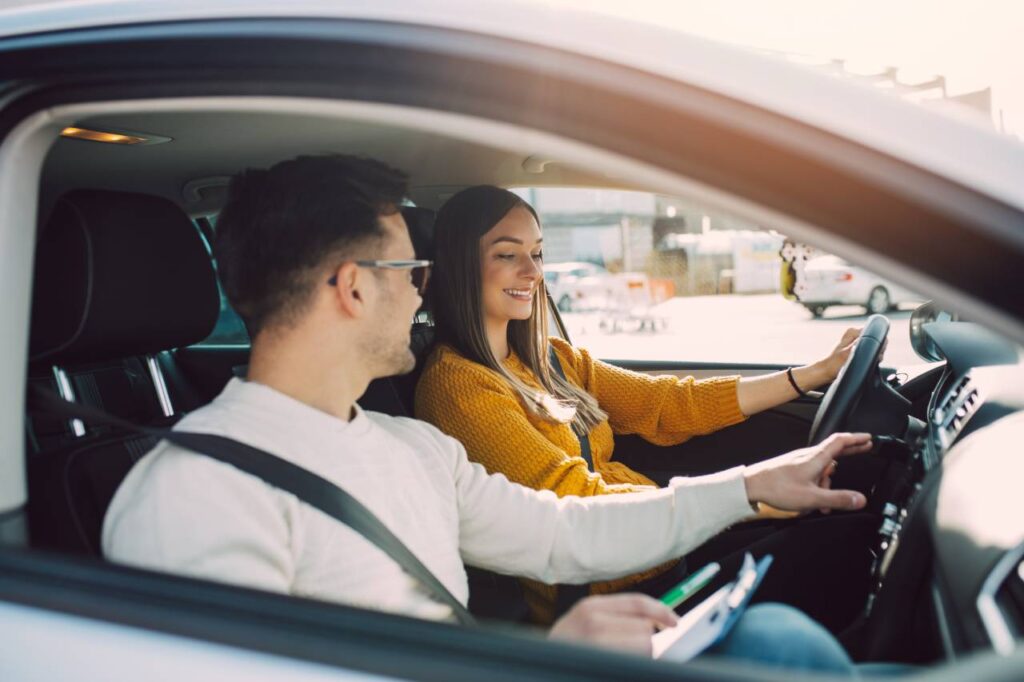 Seguro do carro por quilômetro rodado - homem e mulher felizes dentro de um carro - curso de direção defensiva