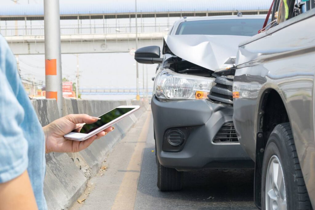 Preço de seguro auto tem queda pelo terceiro mês consecutivo 6 sinistros não cobertos pelo seguro - picape hilux batida atrás de outra picape e mulher segurando celular na mão