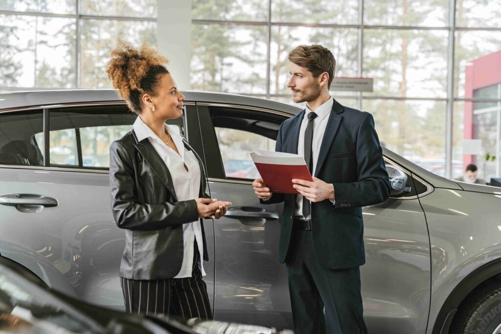 Imagem mostra duas pessoas conversando em frente a um carro, com um documento crv em mãos.
