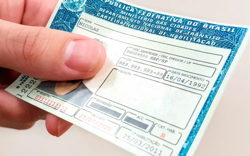 CNH no Brasil: requisitos, processo e importância 2 Pessoa segurando uma carteira de motorista brasileira (CNH) parcialmente preenchida, exibindo dados como nome, data de nascimento, CPF e validade do documento