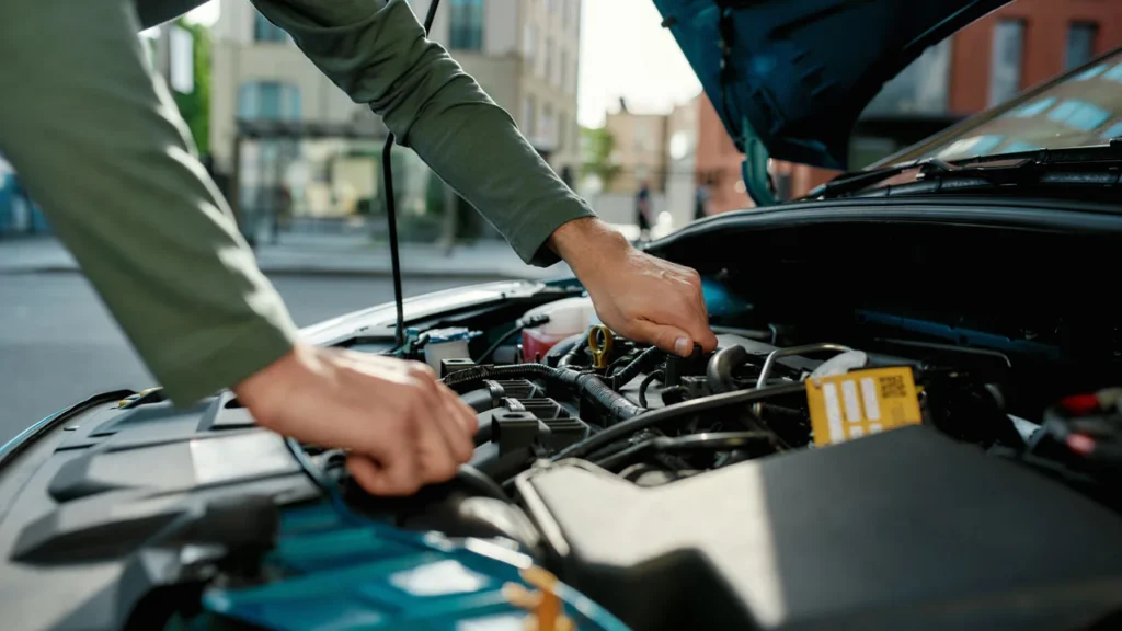 carro com capo aberto enquanto mao masculina mexe no motor - Descubra como equilibrar depreciação x manutenção