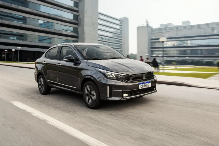 Fiat Cronos Precision cinza escuro em movimento pela cidade, com destaque para a dianteira e design dos faróis