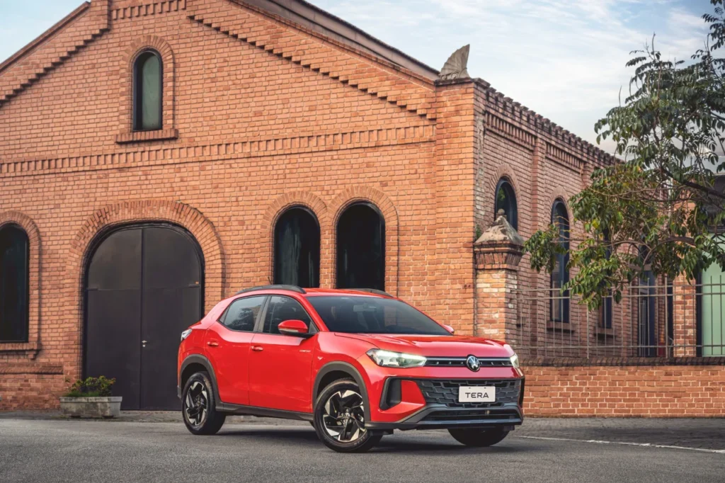 VW Tera vermelho estacionado em frente a construção de tijolos, evidenciando seu visual urbano e elegante.