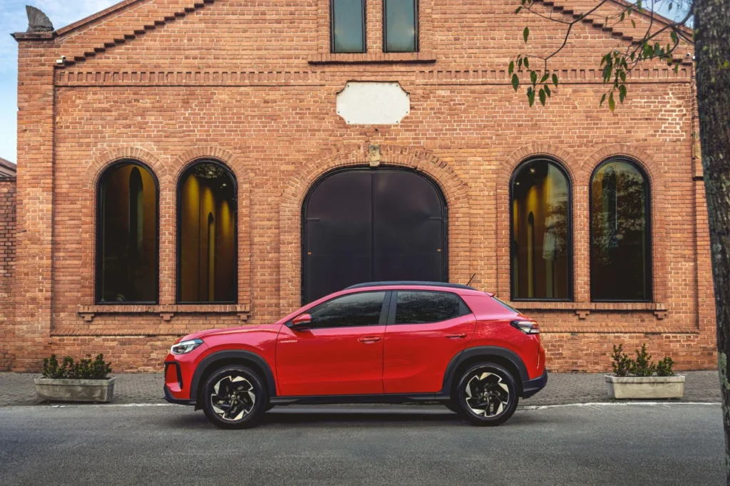 Volkswagen Tera estreia com preços a partir de R$ 99.990 6 Vista lateral completa do VW Tera vermelho, destacando as rodas de liga leve e as linhas marcantes do SUV.