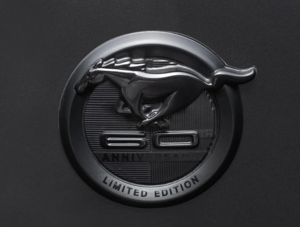 Mustang GT Manual 2025: edição limitada com 492 cv e câmbio manual 5 Emblema de edição limitada dos 60 anos do Ford Mustang com logotipo do cavalo em relevo sobre fundo preto.