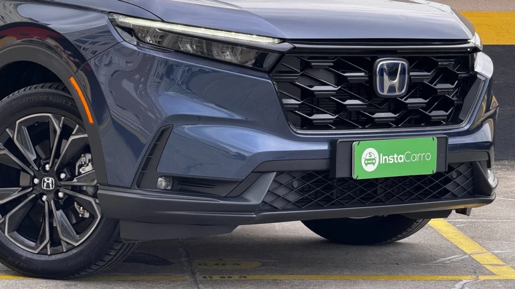 Honda CR-V híbrido 2025: SUV caro, mas com tração integral e alto nível de eficiência 2 Detalhe frontal do Honda CR-V híbrido 2025, com foco na grade, farol e logo da Honda com placa da InstaCarro.