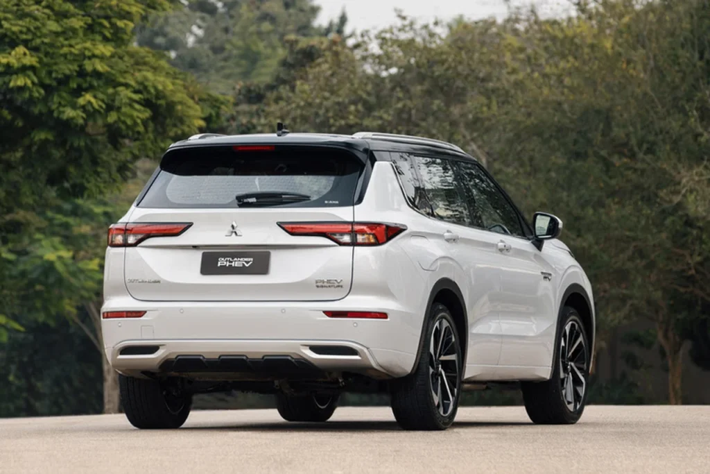 Novo Mitsubishi Outlander 2025 chega ao Brasil com motor híbrido plug-in e até 844 km de autonomia 6 Vista traseira externa do Mitsubishi Outlander PHEV 2025, em um ambiente arborizado, com destaque para as lanternas e o design robusto.