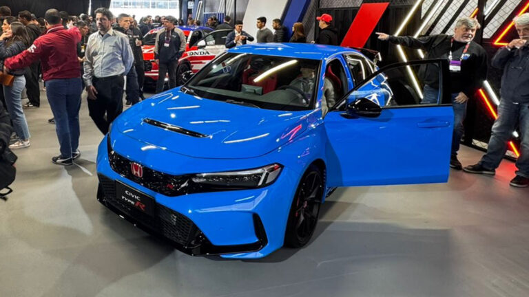 Evento onde a Honda revela 3 novos veículos, com destaque para o modelo Civic Type R azul em exposição, cercado por visitantes e entusiastas da marca.