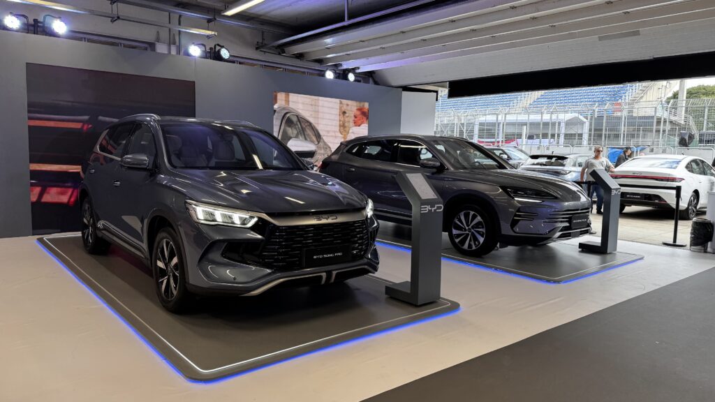 BYD no Festival Interlagos: liderança, tecnologia e produção 1 Feira BYD com exposição de veículos elétricos e híbridos, incluindo os modelos BYD Song Pro e BYD Seal U, em estande iluminado com design moderno e informativo.
