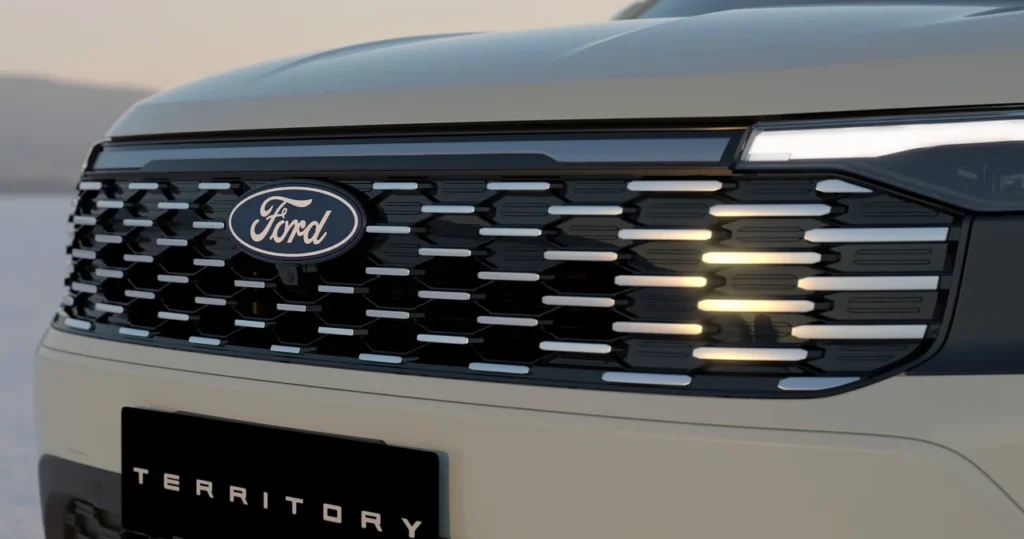 Novo Ford Territory 2026 tem novo visual revelado e estreia confirmada no Brasil 3 Detalhe da grade frontal do Ford Territory com o logotipo da Ford ao centro e faróis de LED acesos