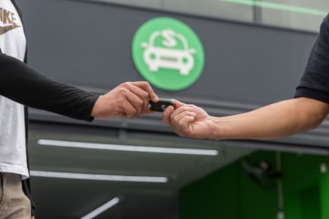 Duas pessoas apertando as mãos, fechando a venda de um carro na frente de uma loja da InstaCarro