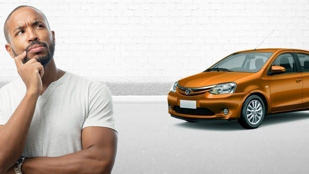 Homem pensativo e um carro laranja ao fundo da imagem