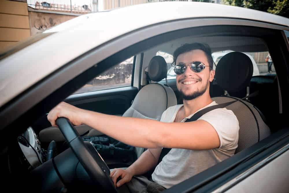 Homem sorrindo dentro do carro