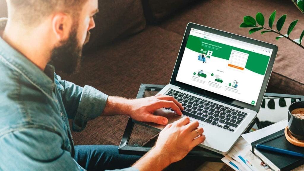 Homem usando notebook com o site da InstaCarro na tela.