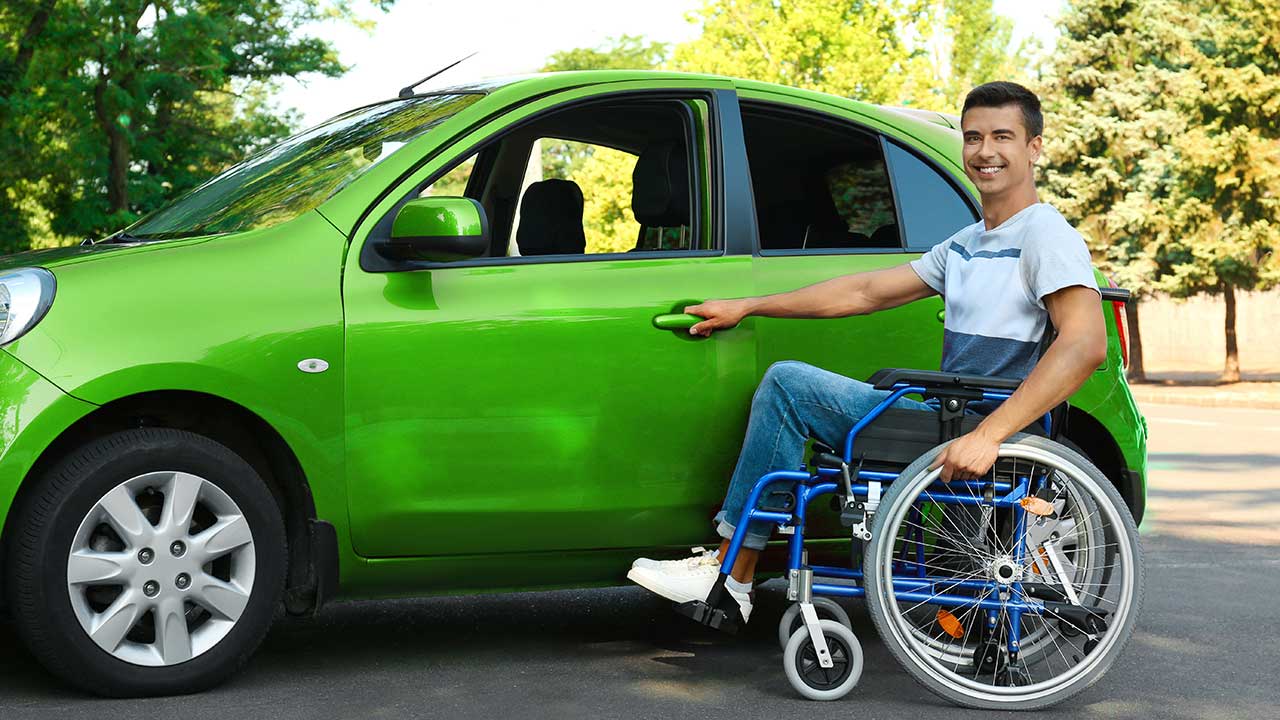 Homem com cadeira de rodas prestes a entrar em um carro verde