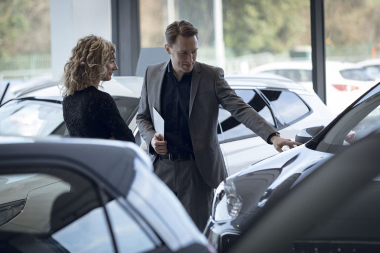 Comprar carro com MEI Vendedor confiante mostrando o carro para o cliente no showroom