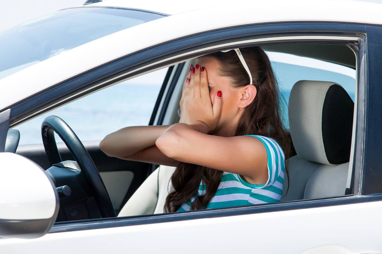 medo de dirigir mulher com as mãos no rosto dentro de um carro