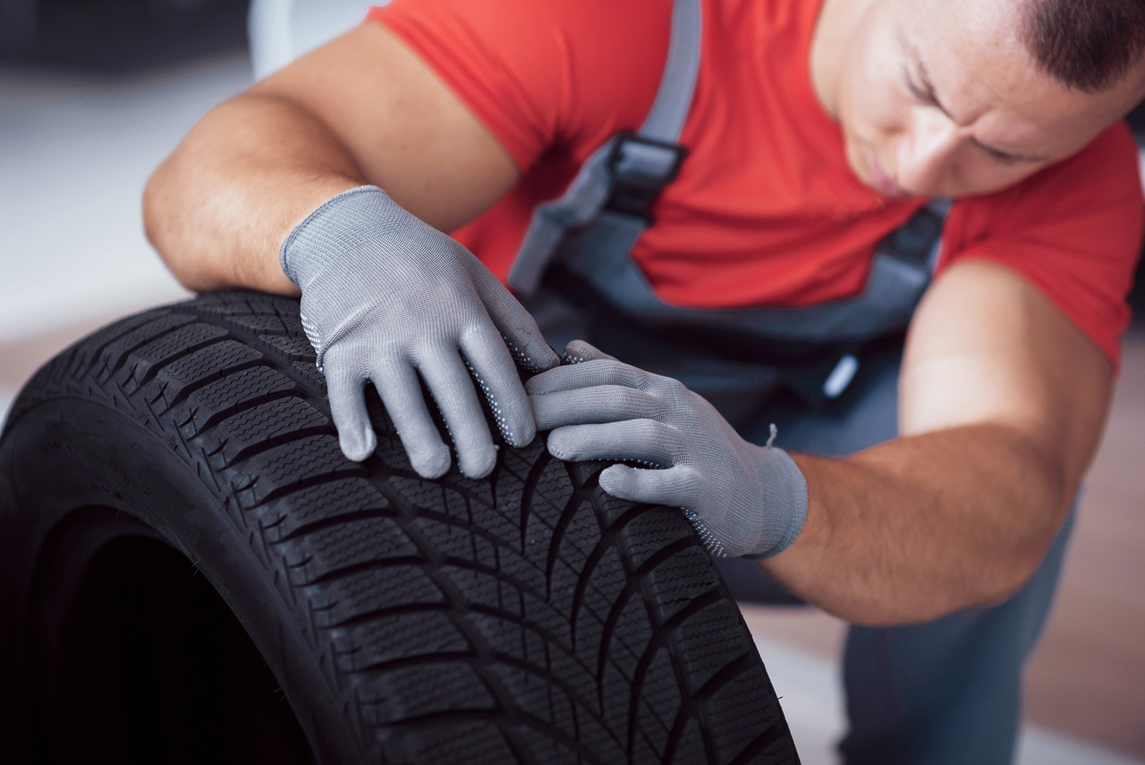 rodizio de pneus - homem conferindo banda de rodagem de pneus